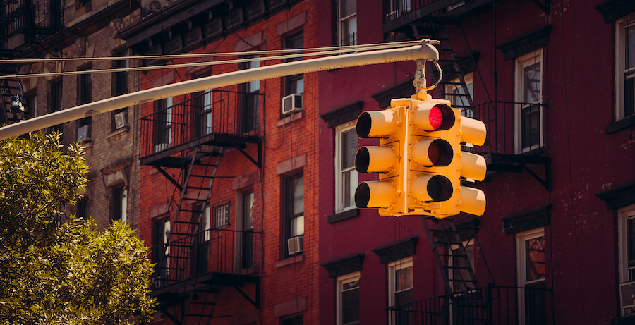 Image of a semaphore with a background of buildings with stairs, meaning that stops are required to avoid fatigue, and related to Hours of Service rules